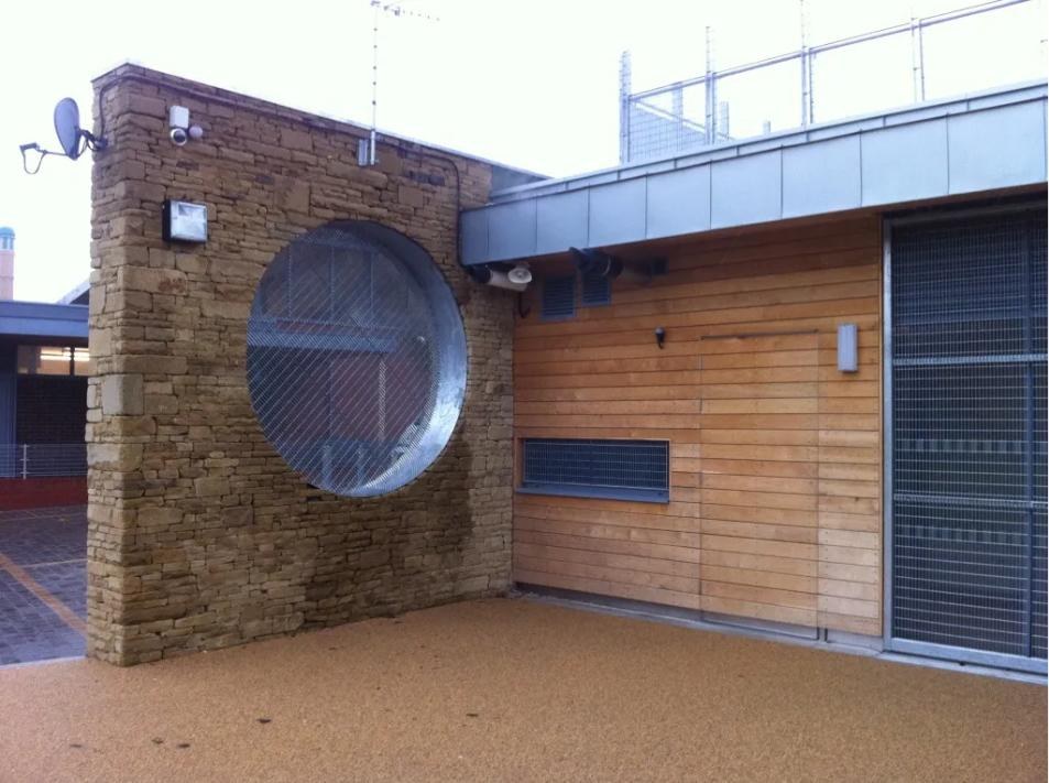 Fabricated galvanised steel ring with mesh infill built into a natural stone wall at a Sheffield youth centre